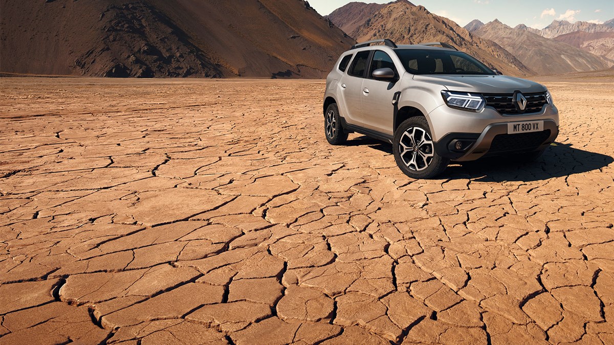 A couple and child with a football are standing in front of the all-new Renault Duster