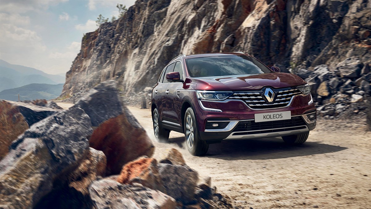 A front corner view of the wine-colored new Renault Koleos running on the rocky hill